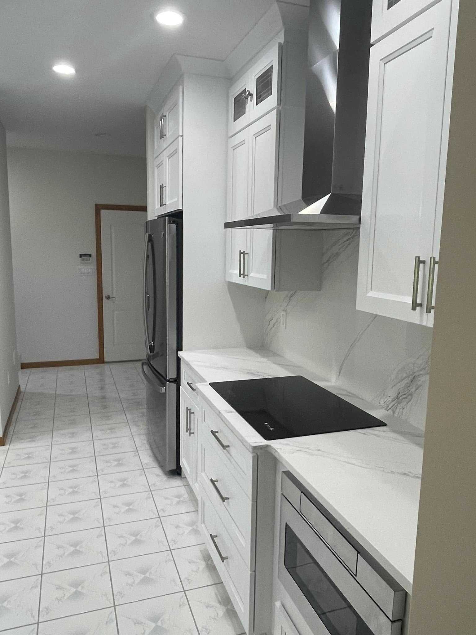Bright, recently completed kitchen with white cabinetry and marble countertops.